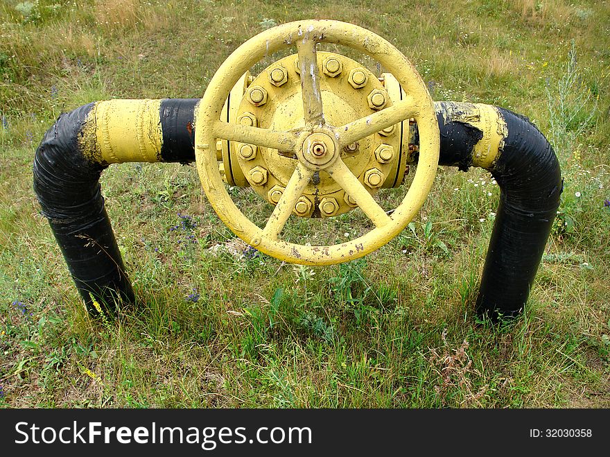 Old gas valve and underground pipeline on the background of dry grass. Old gas valve and underground pipeline on the background of dry grass