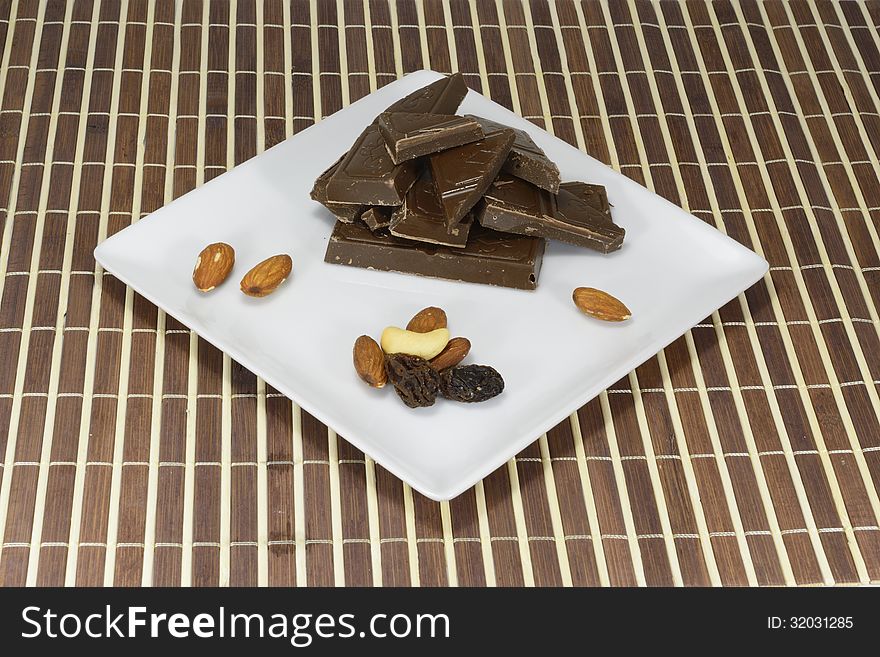 Dark chocolate and nuts with raisin on a white plate. Dark chocolate and nuts with raisin on a white plate
