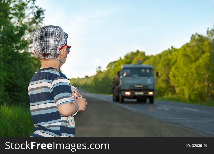 The little boy looks at the moving car. The little boy looks at the moving car