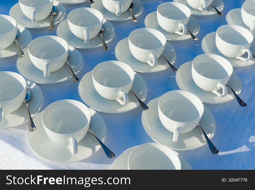 Many rows of pure white cup and saucer with teaspoon, reflection on table. Many rows of pure white cup and saucer with teaspoon, reflection on table