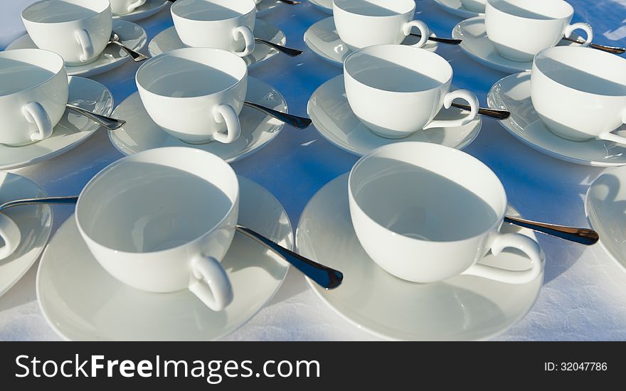 Many rows of pure white cup and saucer with teaspoon, reflection on table. Many rows of pure white cup and saucer with teaspoon, reflection on table