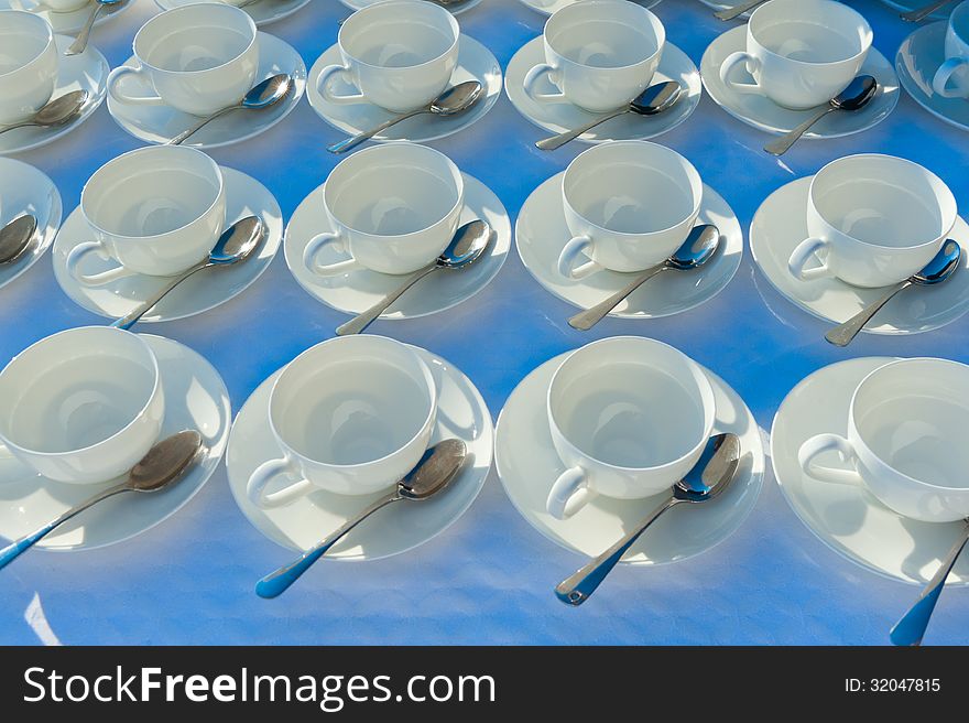 Many rows of pure white cup and saucer with teaspoon, reflection on table. Many rows of pure white cup and saucer with teaspoon, reflection on table