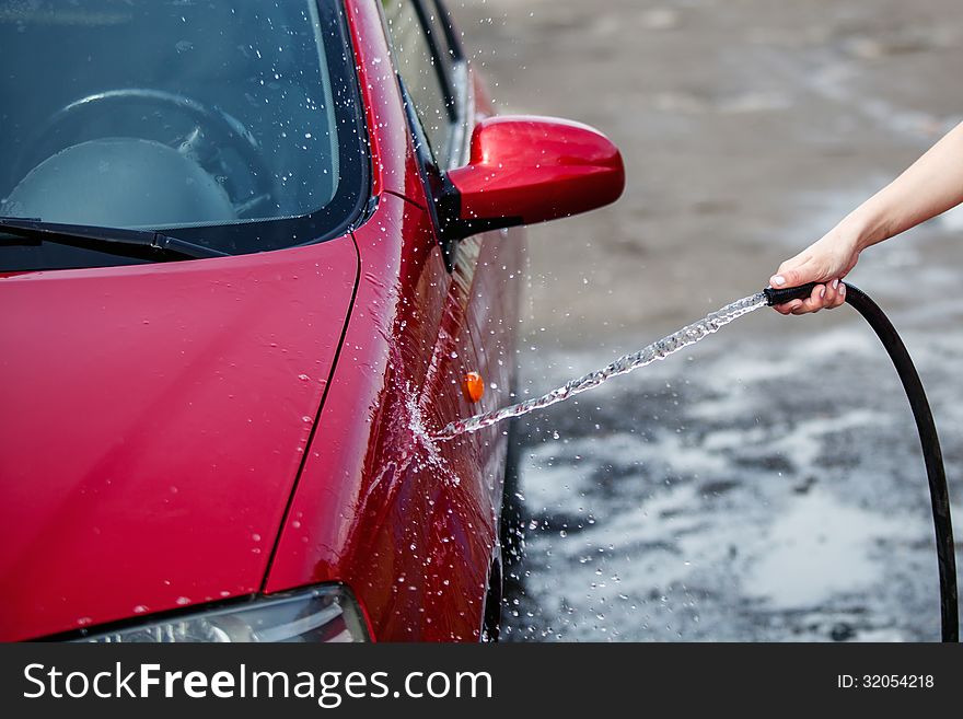 A woman washes a red car on a background asphalt road. A woman washes a red car on a background asphalt road.