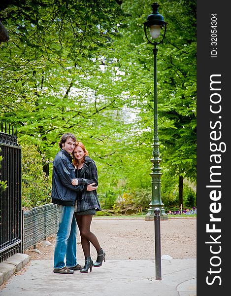 Lovers look at a camera and hugging in Paris in the park near Eiffel Tower. Lovers look at a camera and hugging in Paris in the park near Eiffel Tower