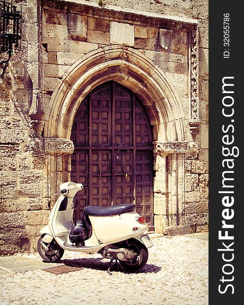 White vintage scooter in front of medieval gate. White vintage scooter in front of medieval gate