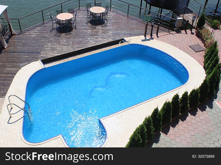 Pool and terace with tables and chairs near lake