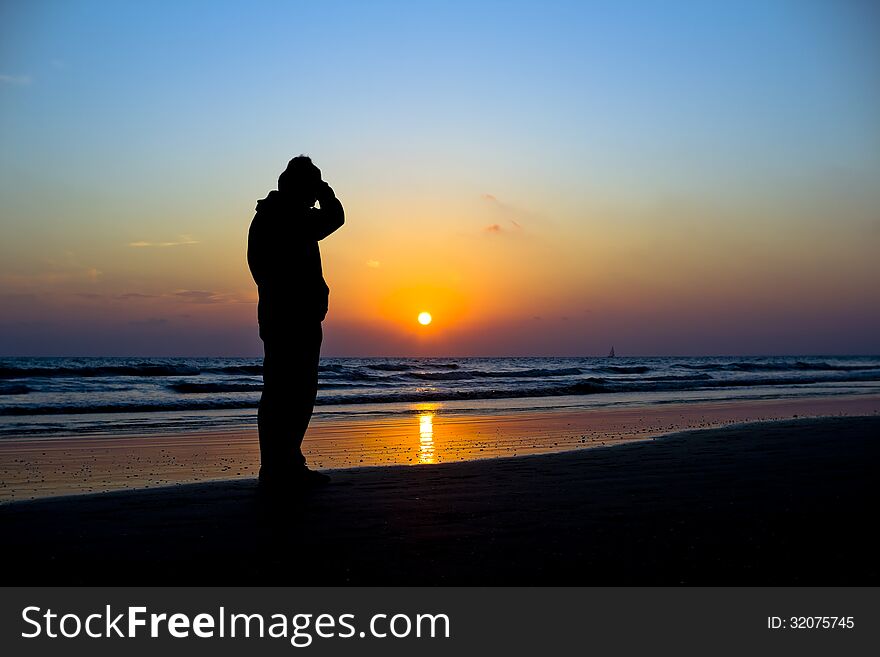 Man silhouetted against a vivid ocean sunset