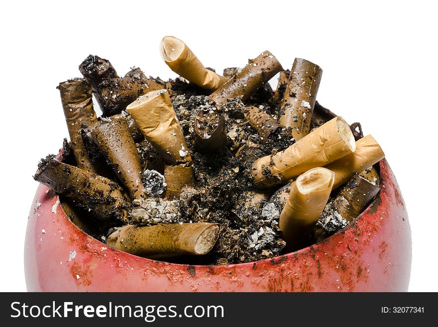 A pile of old and fresh cigarette butts in old, rusty, red ashtray. A pile of old and fresh cigarette butts in old, rusty, red ashtray.