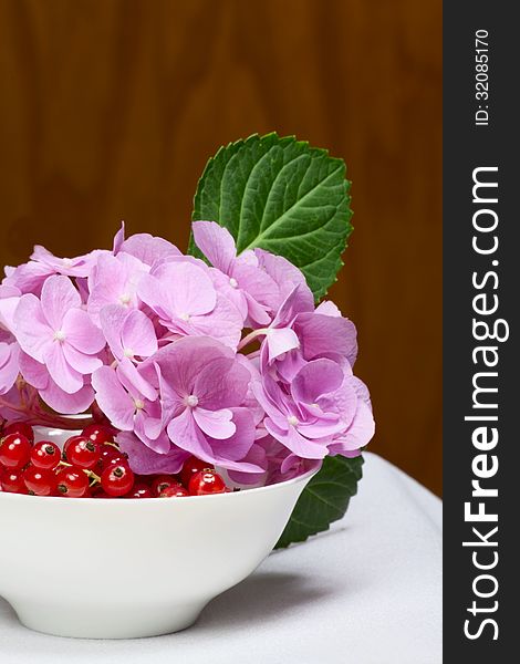 Red currant and pink flowers on a structural wooden background