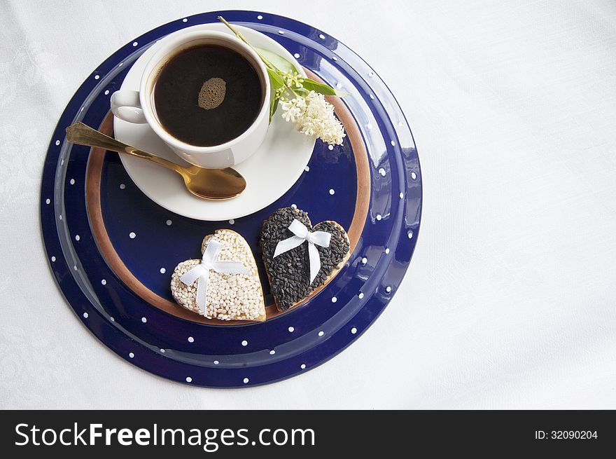 Two wedding cookies with a cup of coffee on the plate
