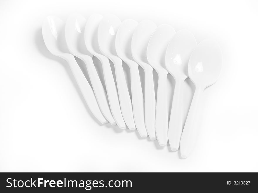 White plastic spoons on white background