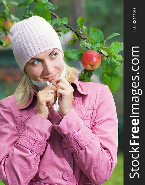 Young girl in pink coat near the apple tree