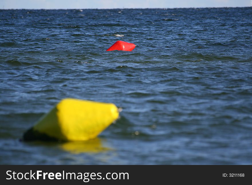 Focus on a red buoy with Yellow one on the blurred foreground. Focus on a red buoy with Yellow one on the blurred foreground