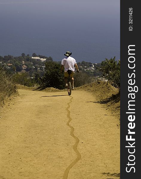 Unicycler and tire tracks on this trail towards the Pacific Ocean. Unicycler and tire tracks on this trail towards the Pacific Ocean