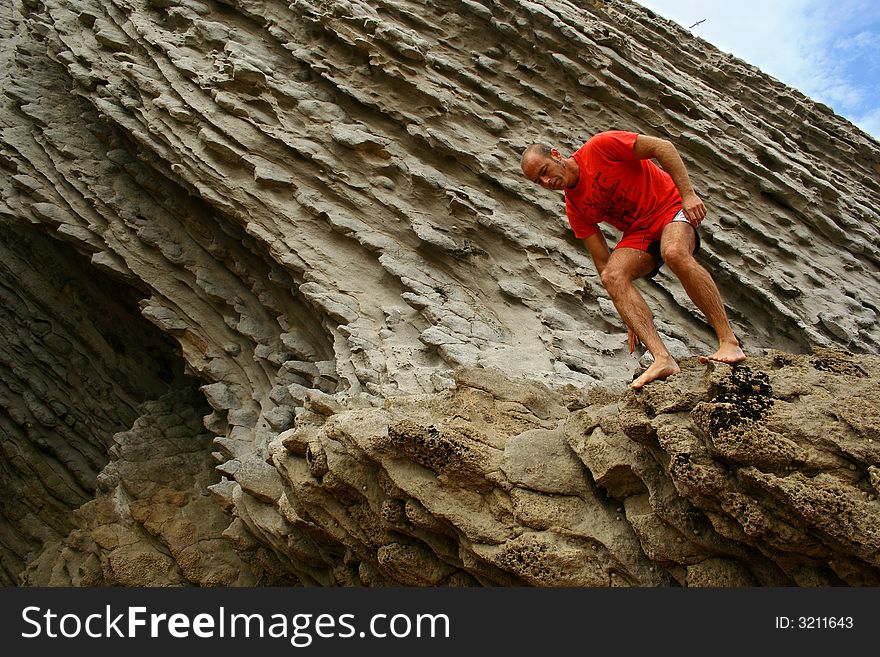 A photo of a young man jumping from the rocks in the beach. A photo of a young man jumping from the rocks in the beach