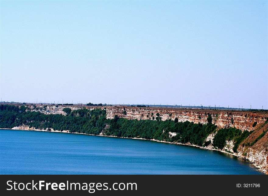 The rocky seashore with a part of blue sea. The rocky seashore with a part of blue sea