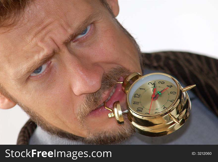 A man keeping an alarm clock in his teeth. A man keeping an alarm clock in his teeth