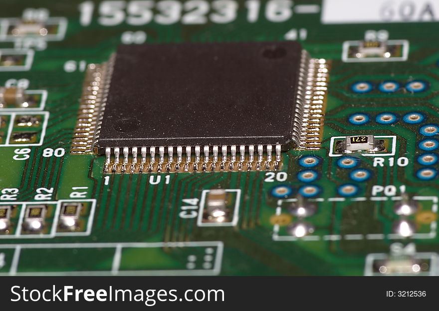 A microchip on green board with a lot of connections