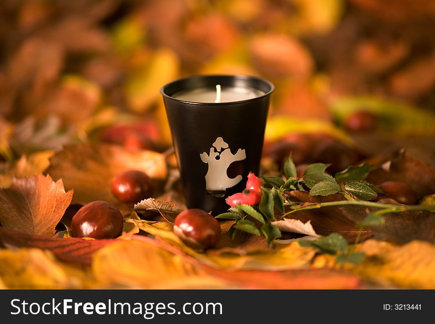 Halloween candle, autumn leaves and chesnuts
