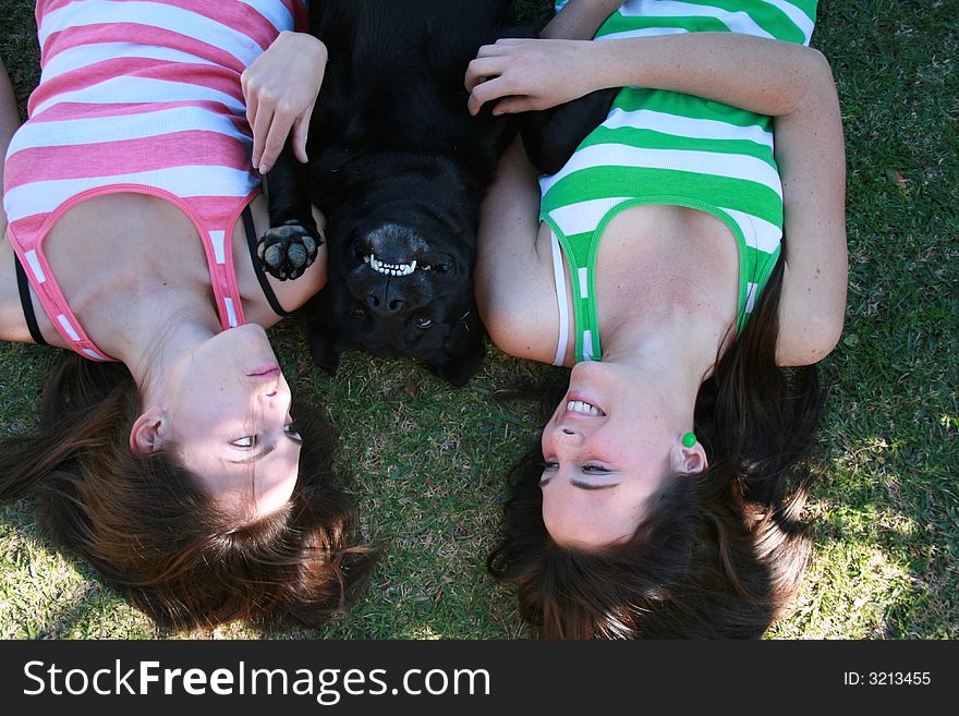 Smiling dog lying in between twin sisters