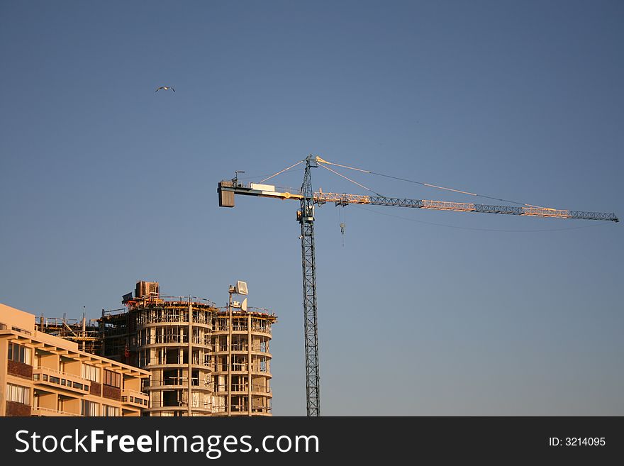 High Crane against a blue sky close to a building site
