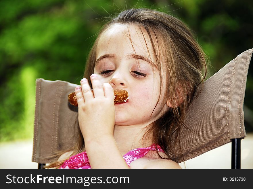 Cute little girl eating a big pretzel in an outdoor setting. Cute little girl eating a big pretzel in an outdoor setting.