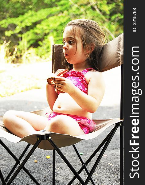 Cute little girl eating a big pretzel in an outdoor setting. Cute little girl eating a big pretzel in an outdoor setting.