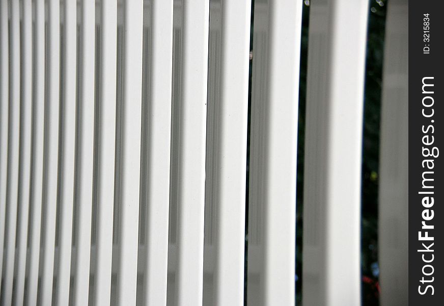 The vertical spindles on our white porch fence photographed in the early evening.