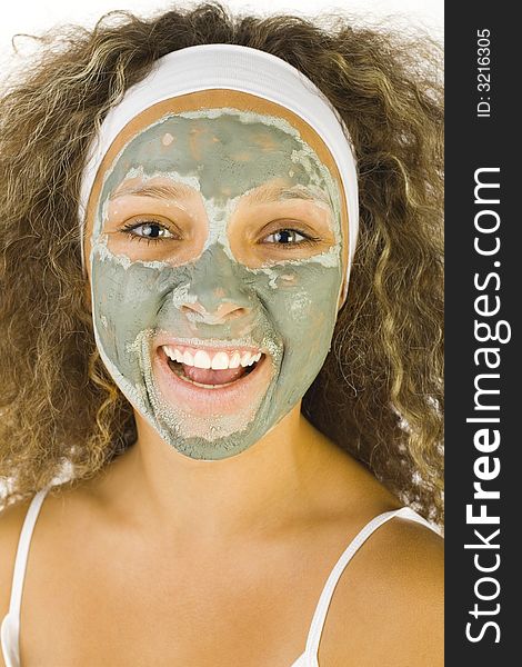 Young happy woman with green purifying mask. She's looking at camera. Young happy woman with green purifying mask. She's looking at camera.