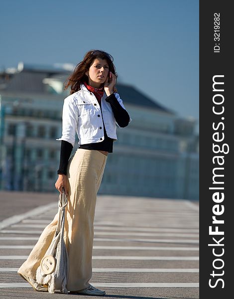 Young beautiful woman walking on empty road an speaking on the telephone. Young beautiful woman walking on empty road an speaking on the telephone