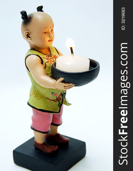 Small chinese figurine in white background white a candle light. Small chinese figurine in white background white a candle light