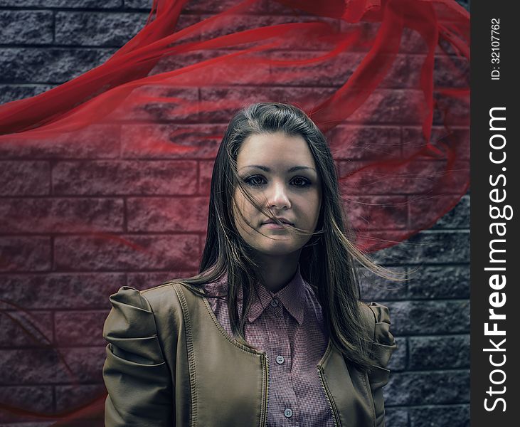 Beautiful girl with hair developing from wind against brick wall with red veil. Beautiful girl with hair developing from wind against brick wall with red veil