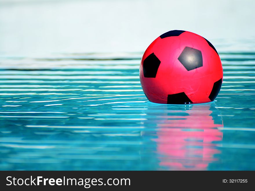 A red ball floating in a swimming pool closeup. A red ball floating in a swimming pool closeup
