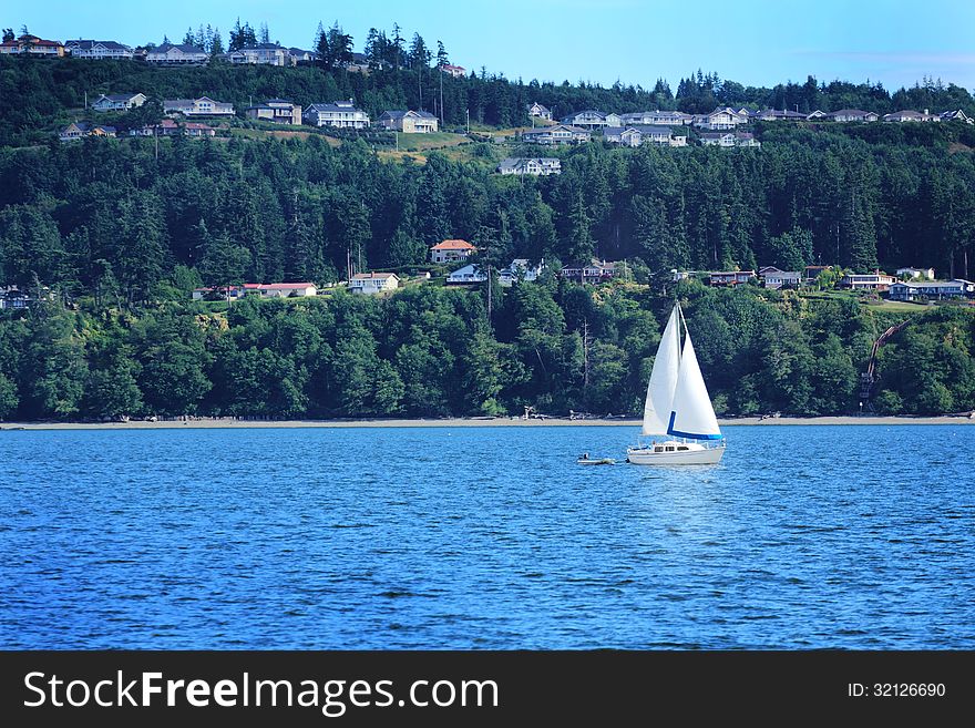 A sailboat under blue skies, view of an island community behind. Copy space. A sailboat under blue skies, view of an island community behind. Copy space.