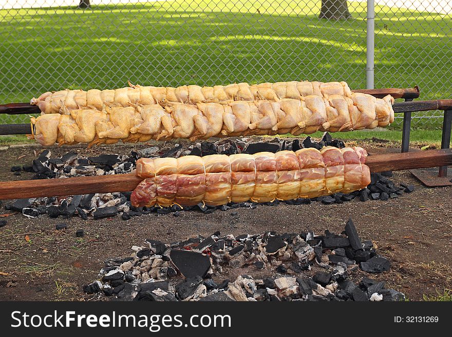 Fresh chicken and pork loin being roasted to a golden brown on a spit, over hot charcoal. Photo taken July 4, 2013. Fresh chicken and pork loin being roasted to a golden brown on a spit, over hot charcoal. Photo taken July 4, 2013.