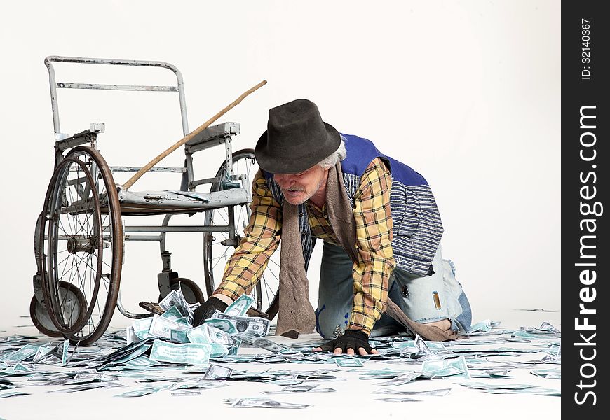 Homeless man with a wheelchair with a lot of money on a white background. Homeless man with a wheelchair with a lot of money on a white background