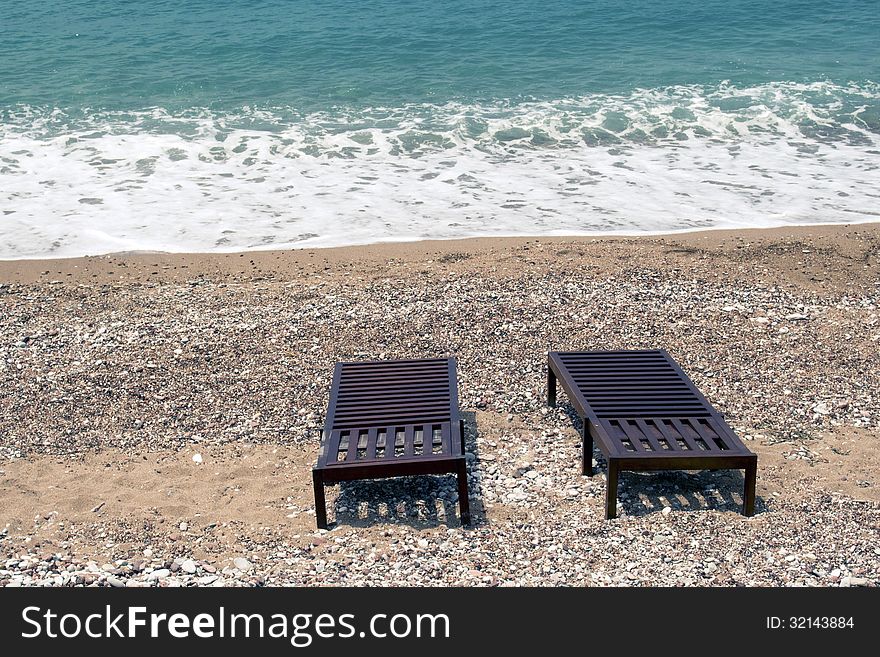 Two sunbeds next to the surf line on sand beach. Two sunbeds next to the surf line on sand beach