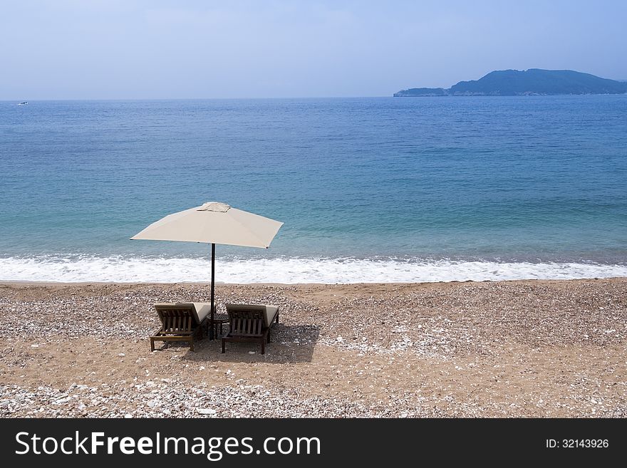 Two sunbeds under sunshade on the empty sand beach. Two sunbeds under sunshade on the empty sand beach