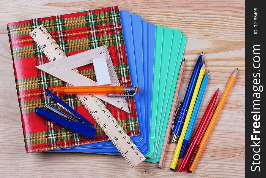 Notebooks,ruler,triangle, pen and pensil on the table