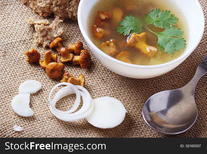 Cup of soup with chanterelles, onion in burlap fabric