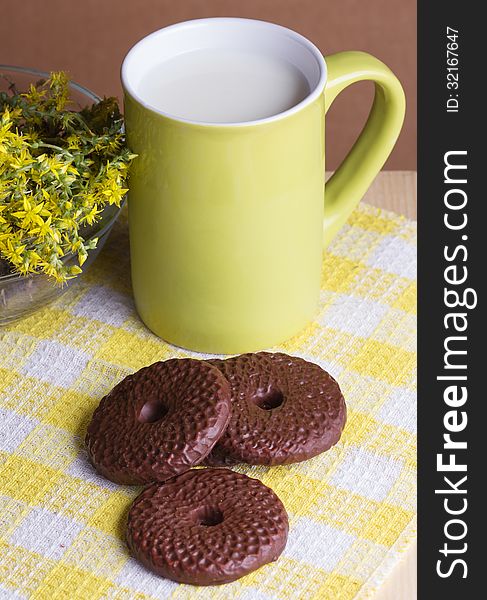 Chocolate cookies and milk, yellow flowers, selective focus. Chocolate cookies and milk, yellow flowers, selective focus