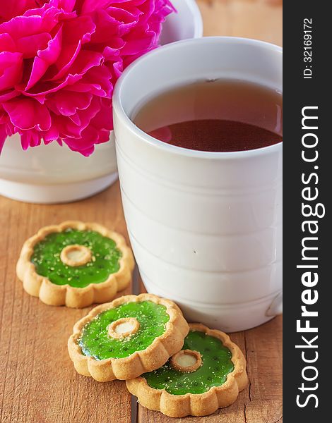 White cup of tea and cookies with green jelly