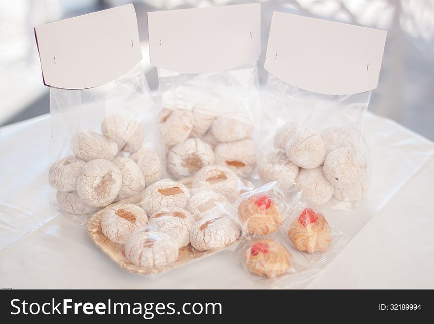 Typical Sicilian sweet cookies packaged in plastic bags on a white table. Typical Sicilian sweet cookies packaged in plastic bags on a white table.