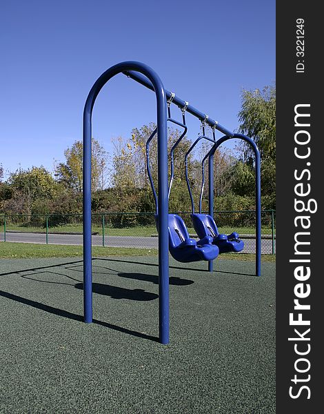 Two empty swings on a public playground.