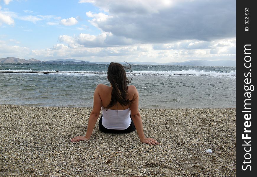 A young woman in the beach in daylight seating on sand. A young woman in the beach in daylight seating on sand