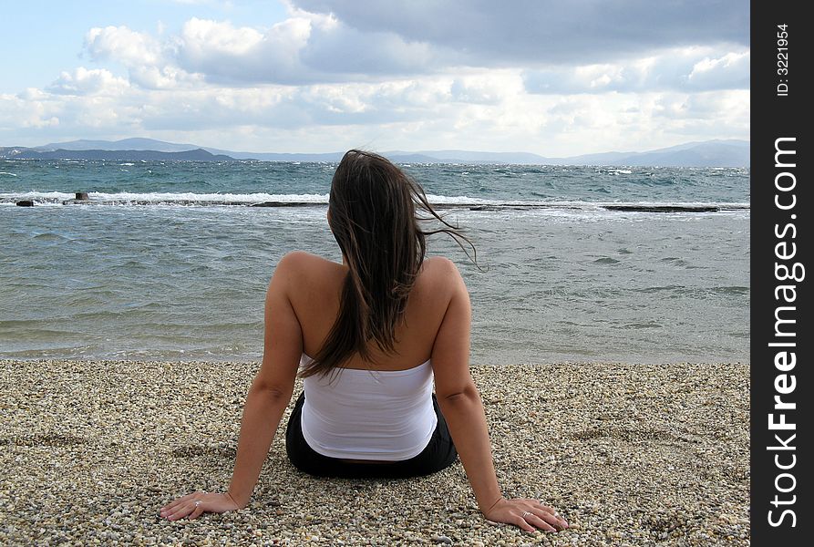 A young woman in the beach in daylight seating on sand. A young woman in the beach in daylight seating on sand