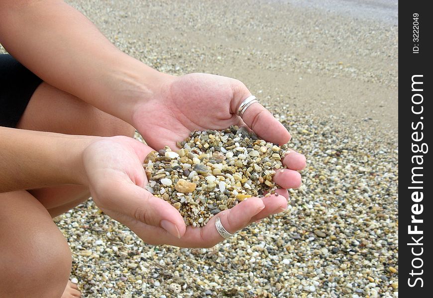 Female hands full of pebbles in the beach. Female hands full of pebbles in the beach