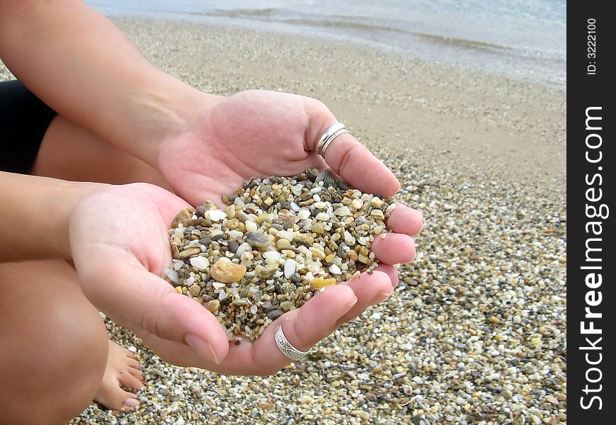 Female hands full of pebbles in the beach. Female hands full of pebbles in the beach