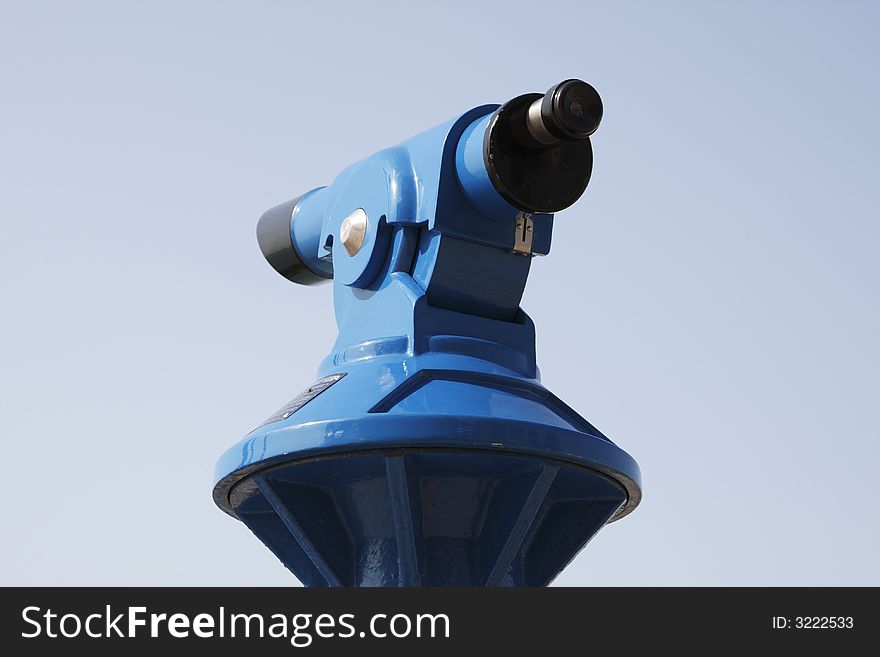 Blue coin operated telescope against a blue sky