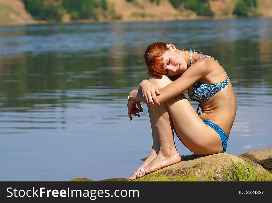 Girl sits on coast of the river